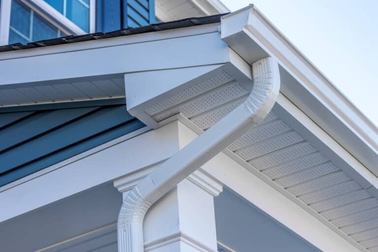 Colonial white gutter guard system, fascia, drip edge, soffit providing ventilation to the attic, with pacific blue vinyl horizontal siding at a luxury American single family home neighborhood USA